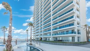 A multi-story hotel with a modern design, featuring balconies and a pool area.