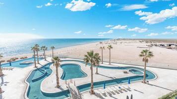 Un complexe hôtelier doté d’une piscine, de palmiers et offrant une vue sur la plage.