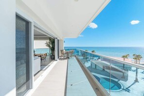 Ein Balkon mit Pool, Essbereich und Meerblick.