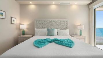 Habitación de hotel con una cama grande, dos mesitas de noche, un cabecero decorativo y vista al océano.