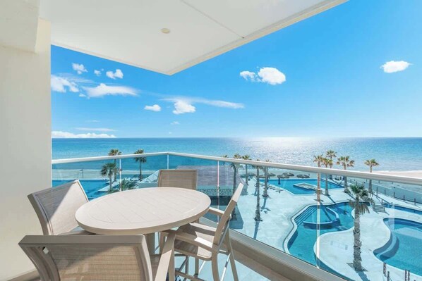 Un balcón con vista a una piscina y al océano.
