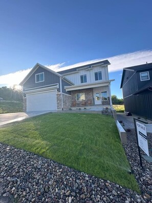 A two-story house with a garage, a stone facade, and a well-maintained lawn. - Sleeps 30 • Hot Tub • Sauna • Pool • Walk to Bear Lake Marina (Garden City)