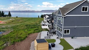 A modern building with a flat roof, large windows, and a covered outdoor seating area. - Sleeps 30 • Hot Tub • Sauna • Pool • Walk to Bear Lake Marina (Garden City)