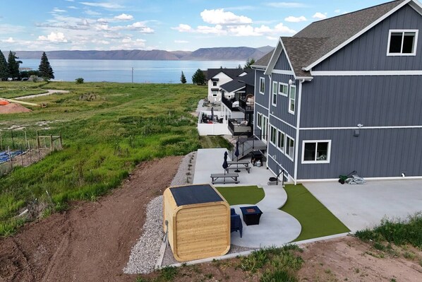 A modern building with a flat roof, large windows, and a covered outdoor seating area. - Sleeps 30 • Hot Tub • Sauna • Pool • Walk to Bear Lake Marina (Garden City)