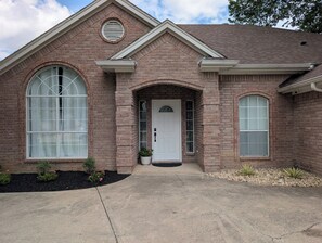 A brick house with a front entrance, large arched windows, and a small porch area.