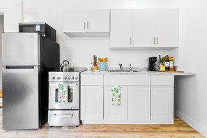 A modern kitchen with stainless steel appliances, white cabinetry, and a wooden floor. - Chic 1BR with Patio/BBQ, Wi-Fi, Free W&D & Parking near NuStadium & MIA Airport (Miami)