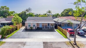 A residential property with a paved driveway, a covered porch, and a fenced backyard. - Chic 1BR with Patio/BBQ, Wi-Fi, Free W&D & Parking near NuStadium & MIA Airport (Miami)