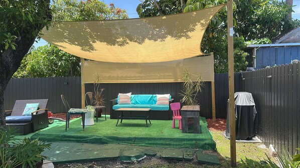 Un jardin avec un canapé, des chaises et une table placés sous un auvent.