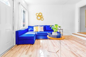 A modern living room with a blue sectional sofa, a round coffee table, and a potted plant. - Chic 1BR with Patio/BBQ, Wi-Fi, Free W&D & Parking near NuStadium & MIA Airport (Miami)
