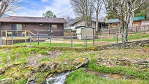 A rustic cabin with a wooden exterior, a small shed, and a fenced yard with a stream. - Crystalwood-Cozy Cabin w/Views+Creek, Easy Access! (Maggie Valley)