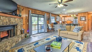 A cozy living room with a stone fireplace, a sofa, a coffee table, and a television. - Crystalwood-Cozy Cabin w/Views+Creek, Easy Access! (Maggie Valley)