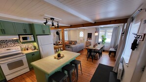A compact kitchen with a central island, a dining area with a table and chairs, and a cozy living space with a sofa and a fireplace. - L'Ancestrale (view, spa, arcade) (La Malbaie)