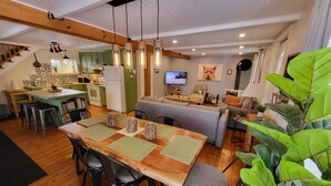 A modern kitchen with green cabinets, a wooden dining table, and a grey sofa in the living area. - L'Ancestrale (view, spa, arcade) (La Malbaie)