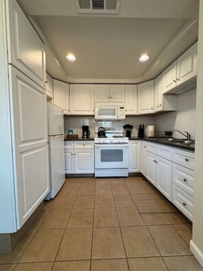 A kitchen with white cabinets, a microwave, a stove, and a sink.