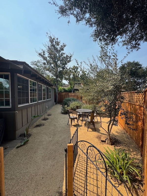 A backyard with a patio, a wooden fence, and a building with large windows.