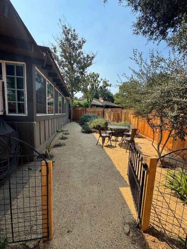 A backyard with a gravel path, wooden fence, and a table with chairs.