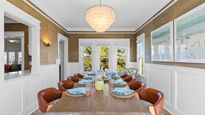 Une salle à manger avec une longue table en bois, des chaises en cuir marron et un lustre.