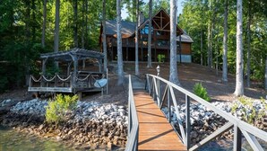 Une terrasse en bois menant à un chalet entouré d’arbres.