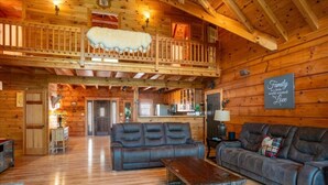 L’intérieur d’une cabane en rondins comprend un espace nuit en mezzanine, un coin repas et un salon avec des canapés en cuir.
