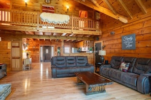 A log cabin interior with a loft bedroom, a dining area, and a living room with leather sofas. - Cedar Cove on Lake Keowee! (Sunset)