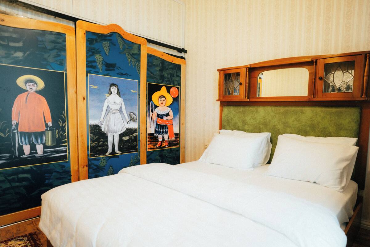 Una habitación de hotel con una cama grande, cabecero de madera y tres cuadros coloridos en la pared.