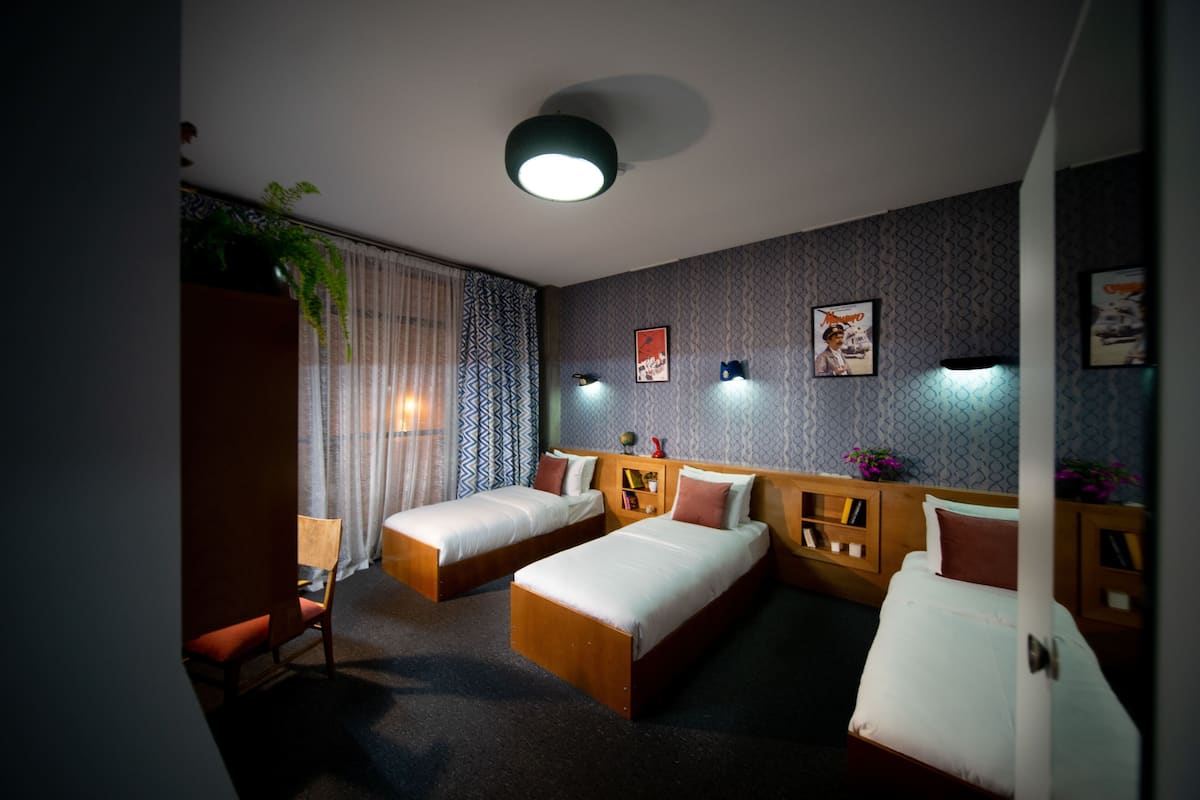 Una habitación de hotel con dos camas individuales, cabecera de madera, un escritorio pequeño y una silla.
