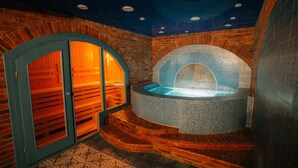 Ett spaområde med ett kaklat bubbelbad, träbänkar och ett mönstrat golv.