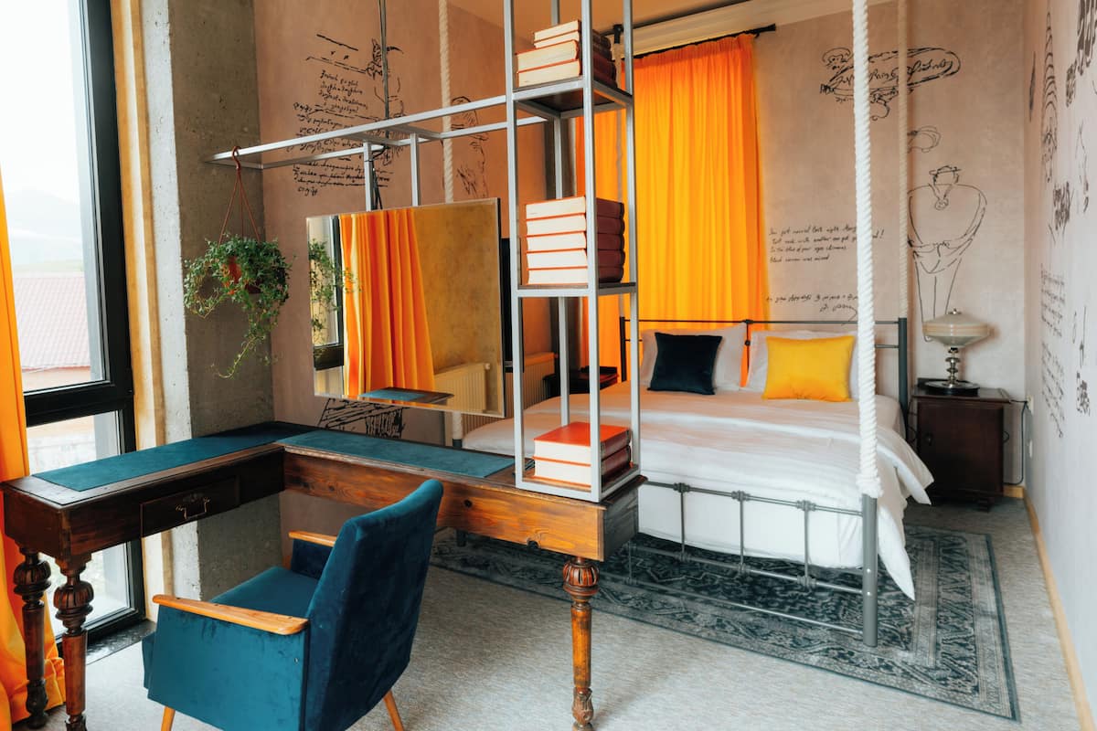 Un dormitorio con una cama litera, un escritorio con silla, un espejo y una mesita de noche con lámpara.