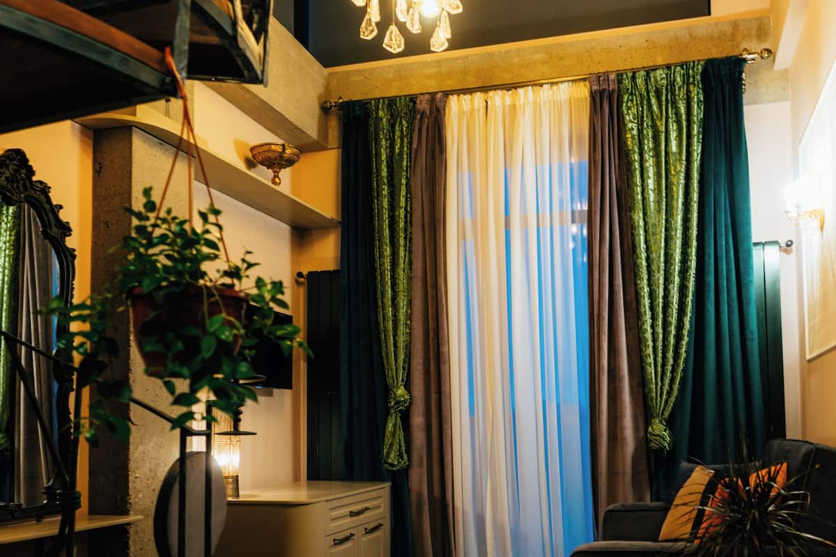 Una sala de estar moderna con una escalera, una araña y un gran ventanal con cortinas.