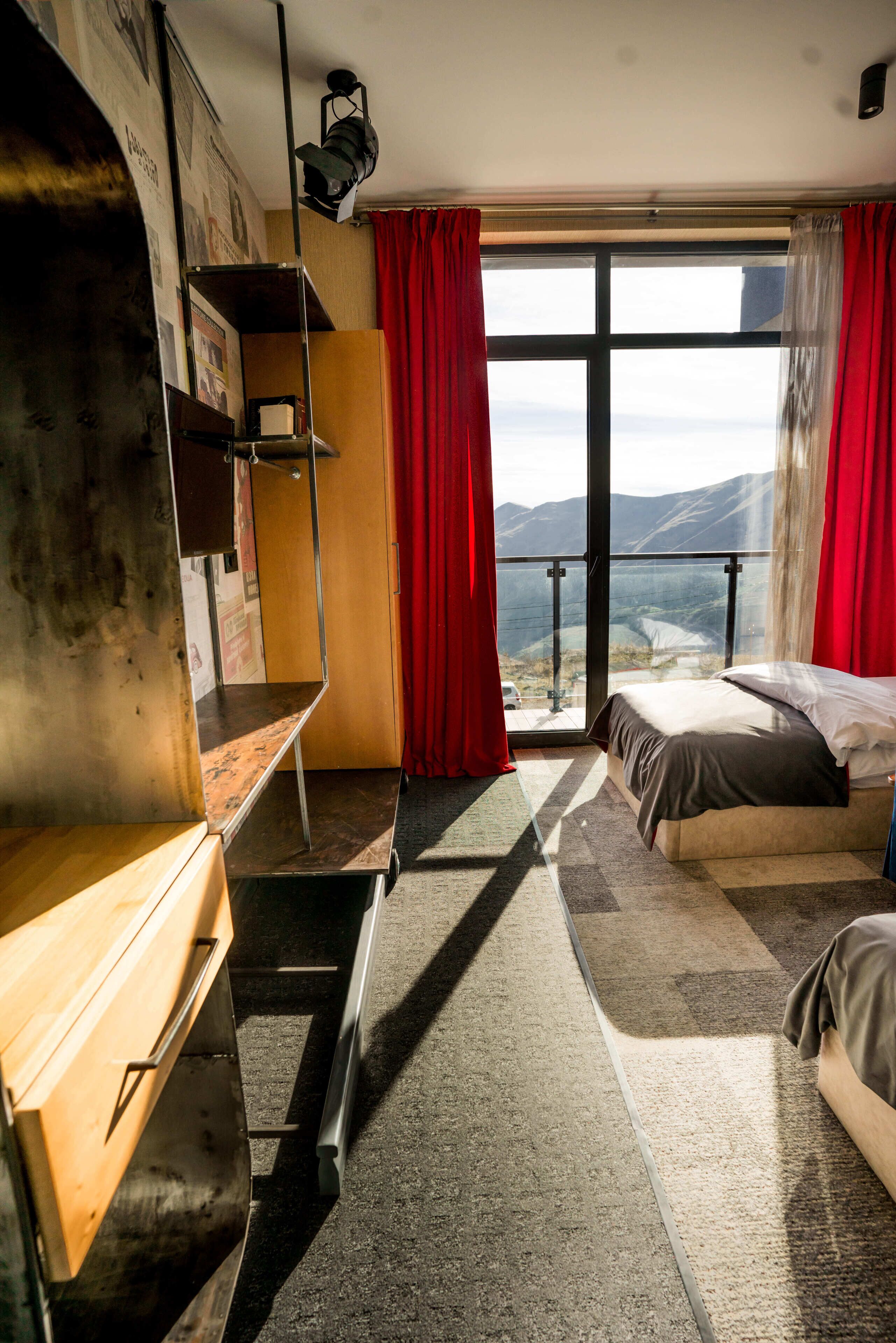 Un dormitorio con una ventana grande, una cama, un escritorio y vistas al exterior.