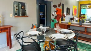 Un coin repas avec une table en verre dressée pour six personnes, entourée de chaises noires.