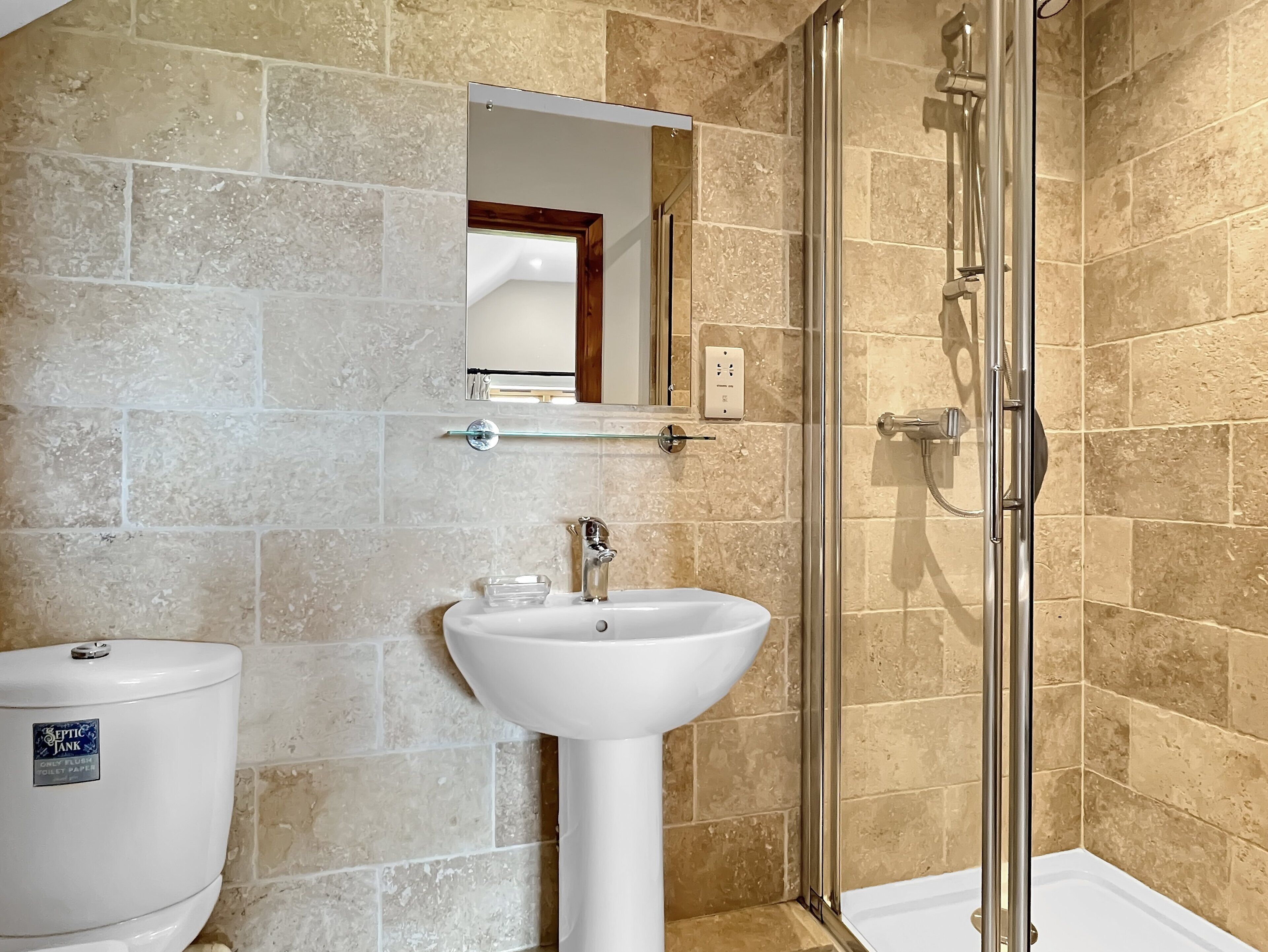 Une salle de bain équipée de toilettes, d’un lavabo et d’une douche à parois de verre.
