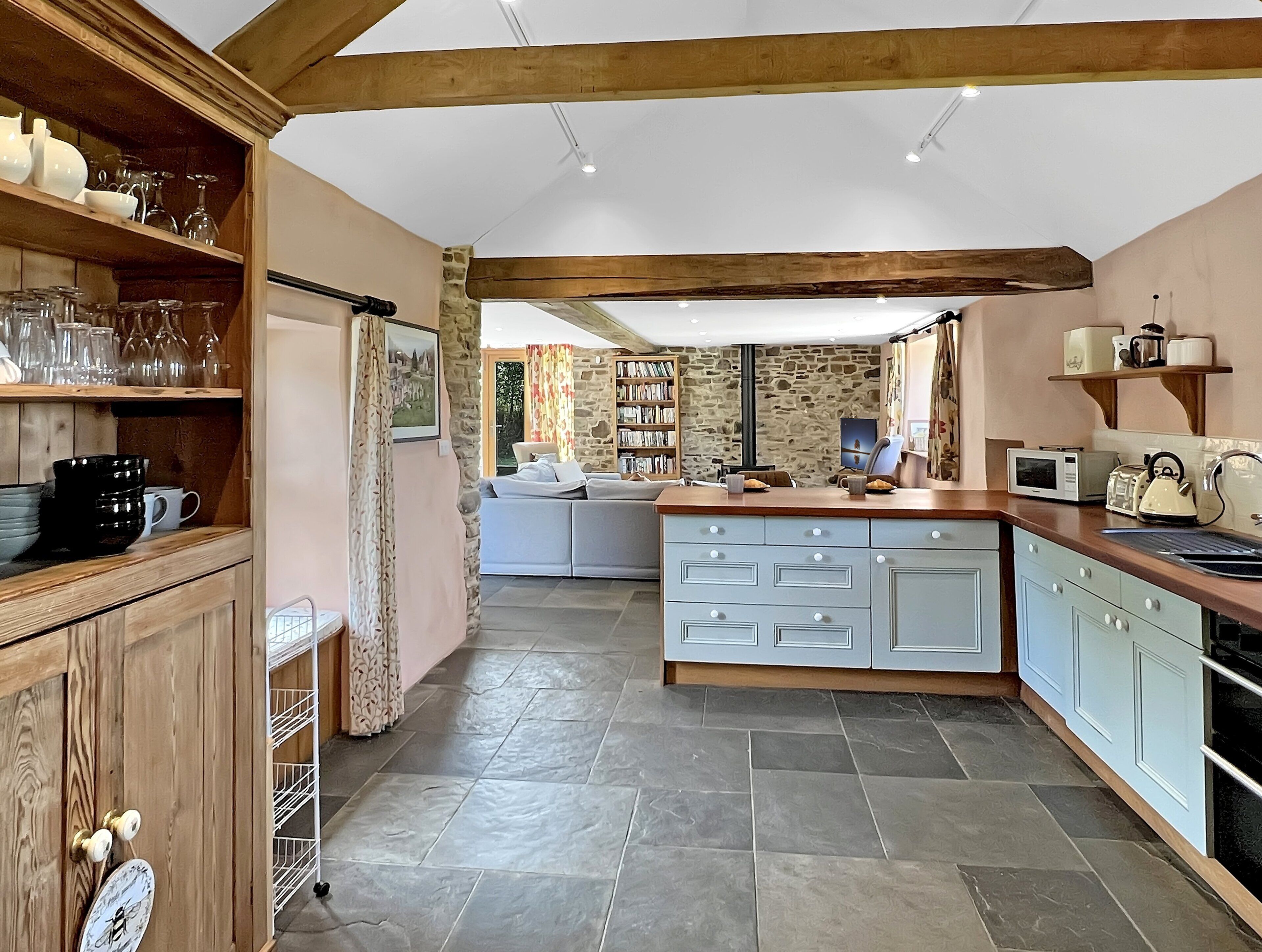 A kitchen with a central island, a dining area with a sofa, and a stone wall.