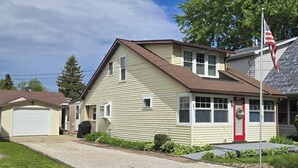 Une maison de plain-pied avec une porte d’entrée rouge, un garage et un mât sur lequel flotte le drapeau américain.