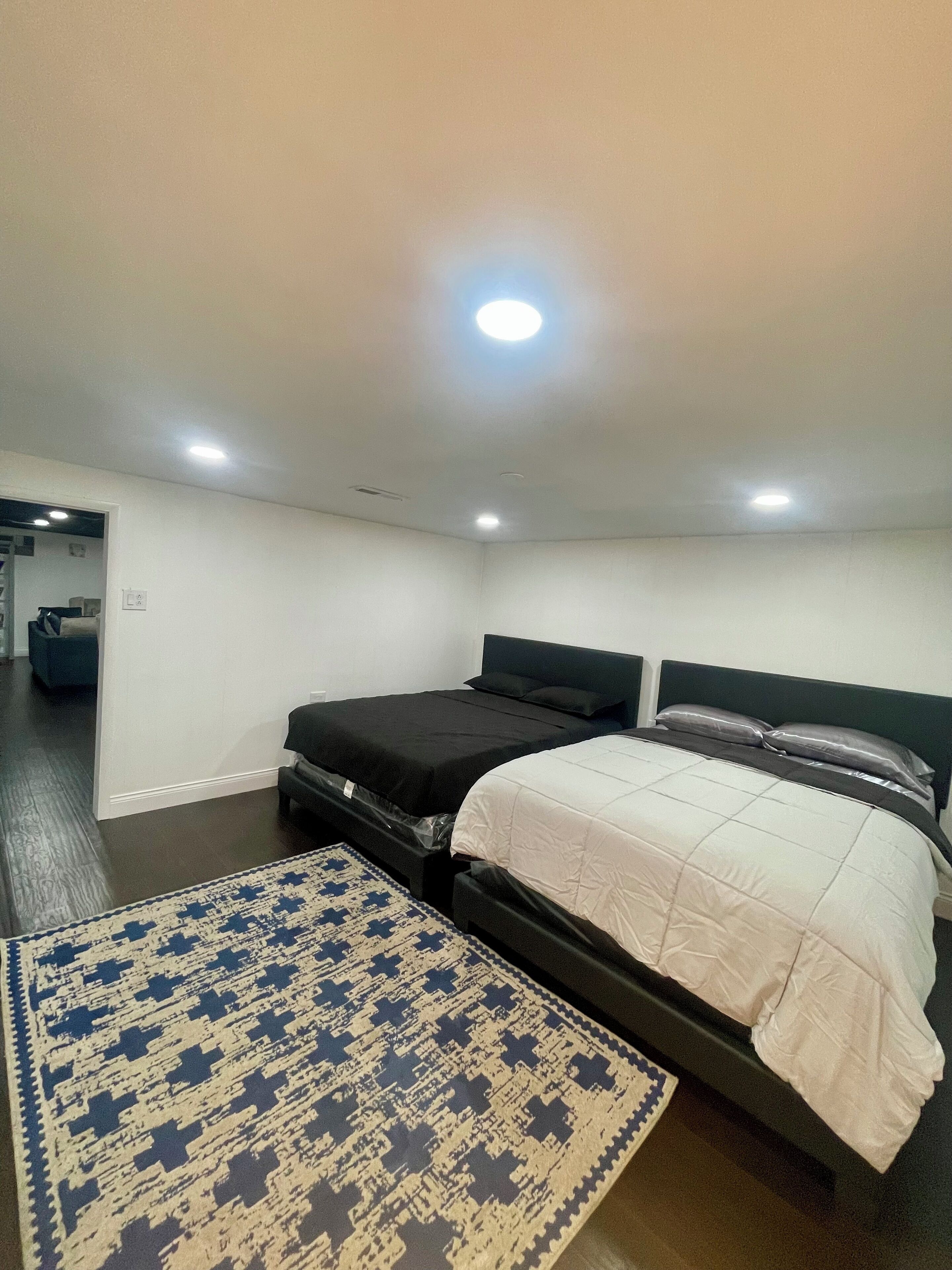 Une chambre avec deux lits, un tapis à motifs et un couloir menant à une salle de bain.