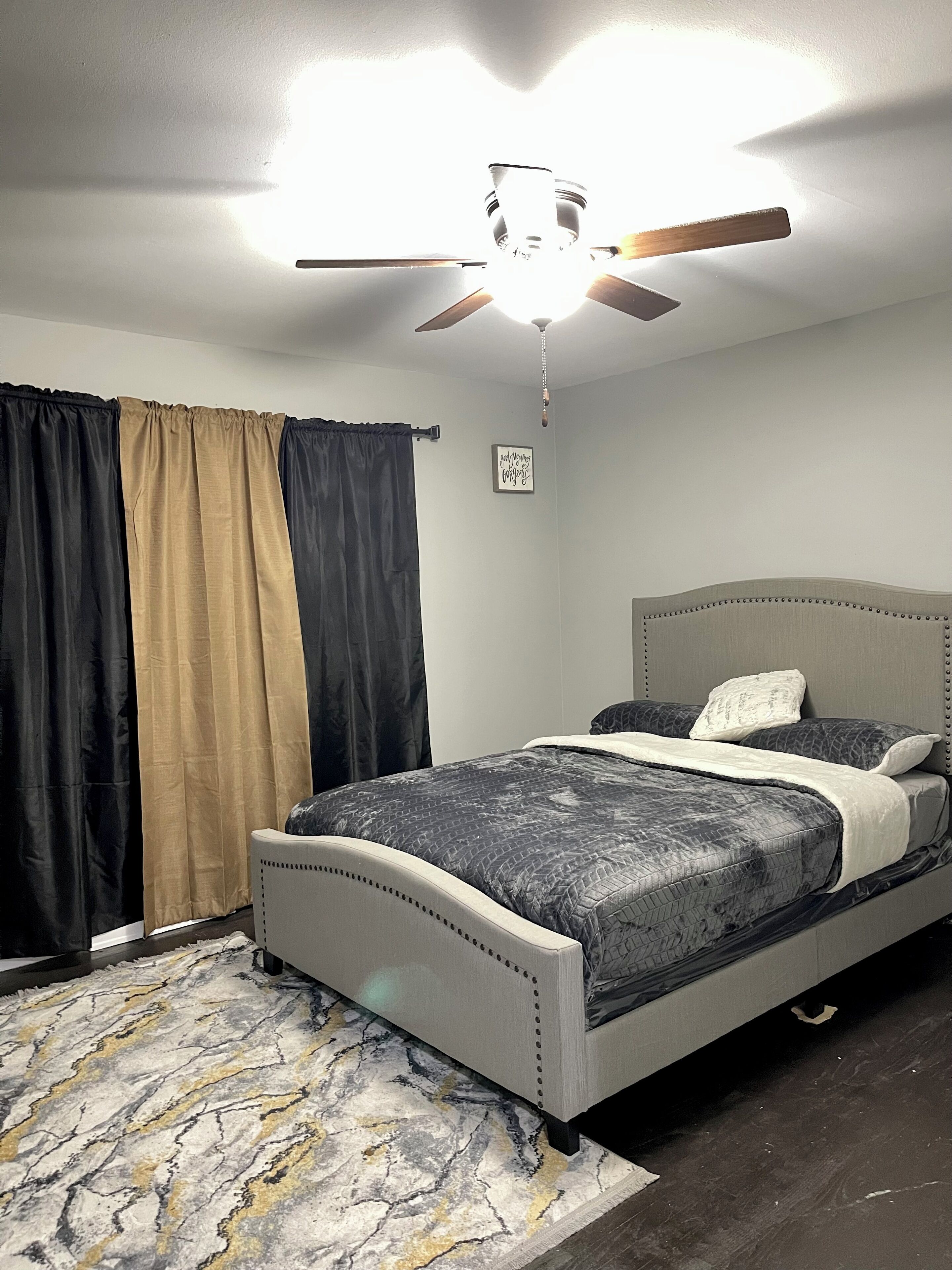 Ein Schlafzimmer mit einem Bett, einem Deckenventilator und einem Teppich.