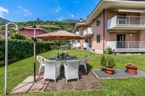 A patio with a table and chairs, a pergola, and a view of a residential building with a balcony.