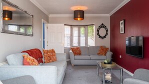 Een woonkamer met twee grijze banken, een salontafel, een televisie en een spiegel.