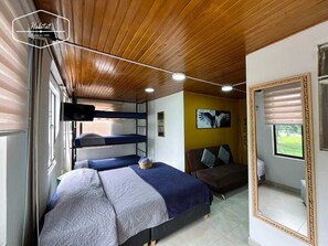 Un dormitorio con literas, un sofá, un espejo y una ventana con vistas.
