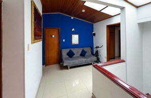Een kamer met een blauwe accentmuur, een grijze bank, een houten deur en een fiets.