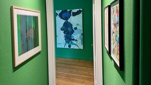 Um corredor com paredes verdes, soalho de madeira e obras de arte emolduradas.