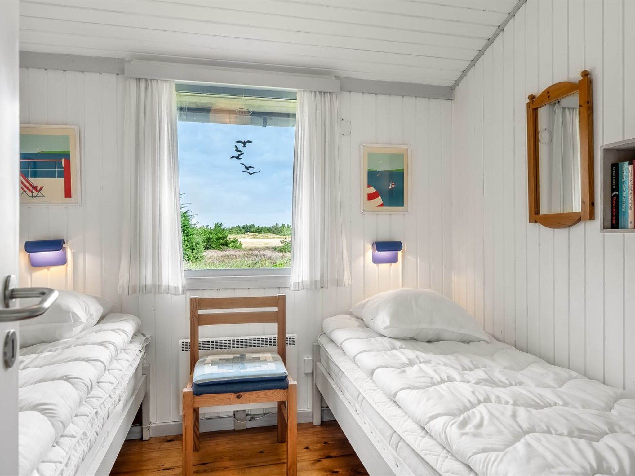 Une chambre avec deux lits simples, une chaise en bois, une fenêtre avec des rideaux et des lampes fixées au mur.