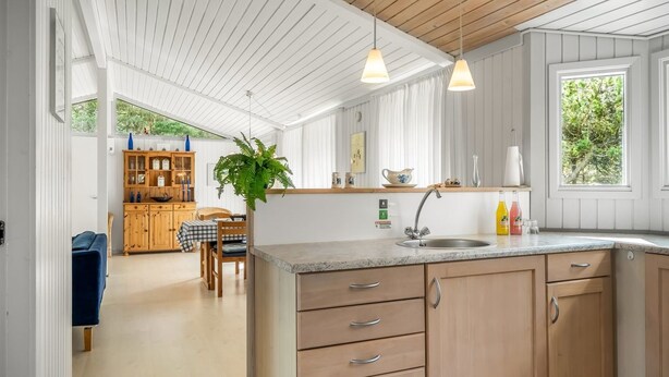 Eine moderne Küche mit Holzschränken, einer Granitarbeitsplatte und Pendelleuchten.