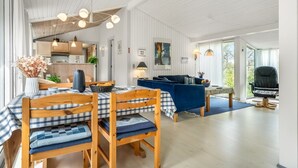 Ein geräumiger Wohnbereich mit Esstisch für vier Personen, einem blauen Sofa und einem schwarzen Ledersessel.