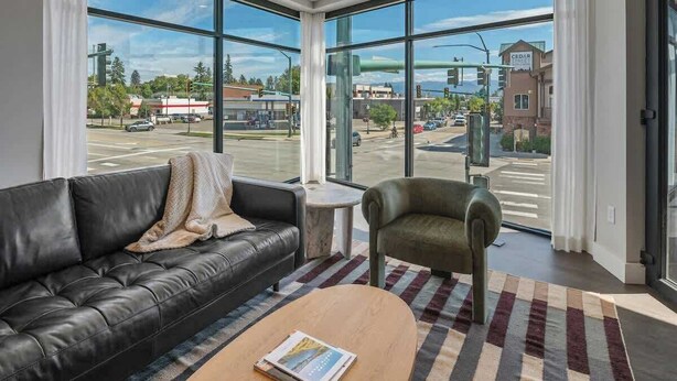 A modern living room with a leather sofa, a small round table, and a view of Cedar Street.