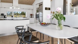 Una cocina moderna con armarios blancos, una isla grande y un comedor con sillas negras.