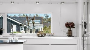 Una cocina moderna con un amplio ventanal, armarios blancos y un lavamanos de acero inoxidable.