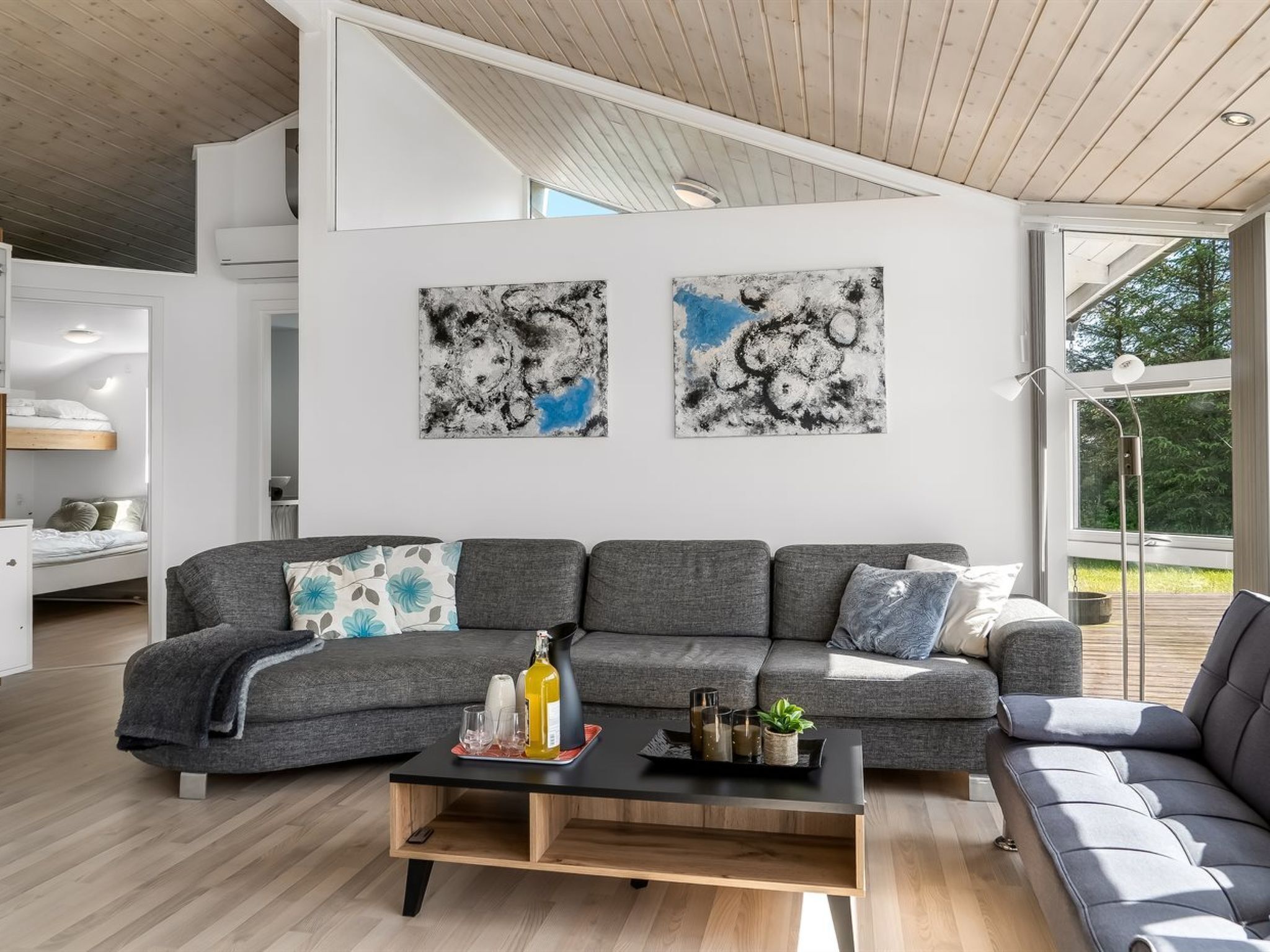 A modern living room with a grey sectional sofa, a wooden coffee table, and abstract art on the wall.