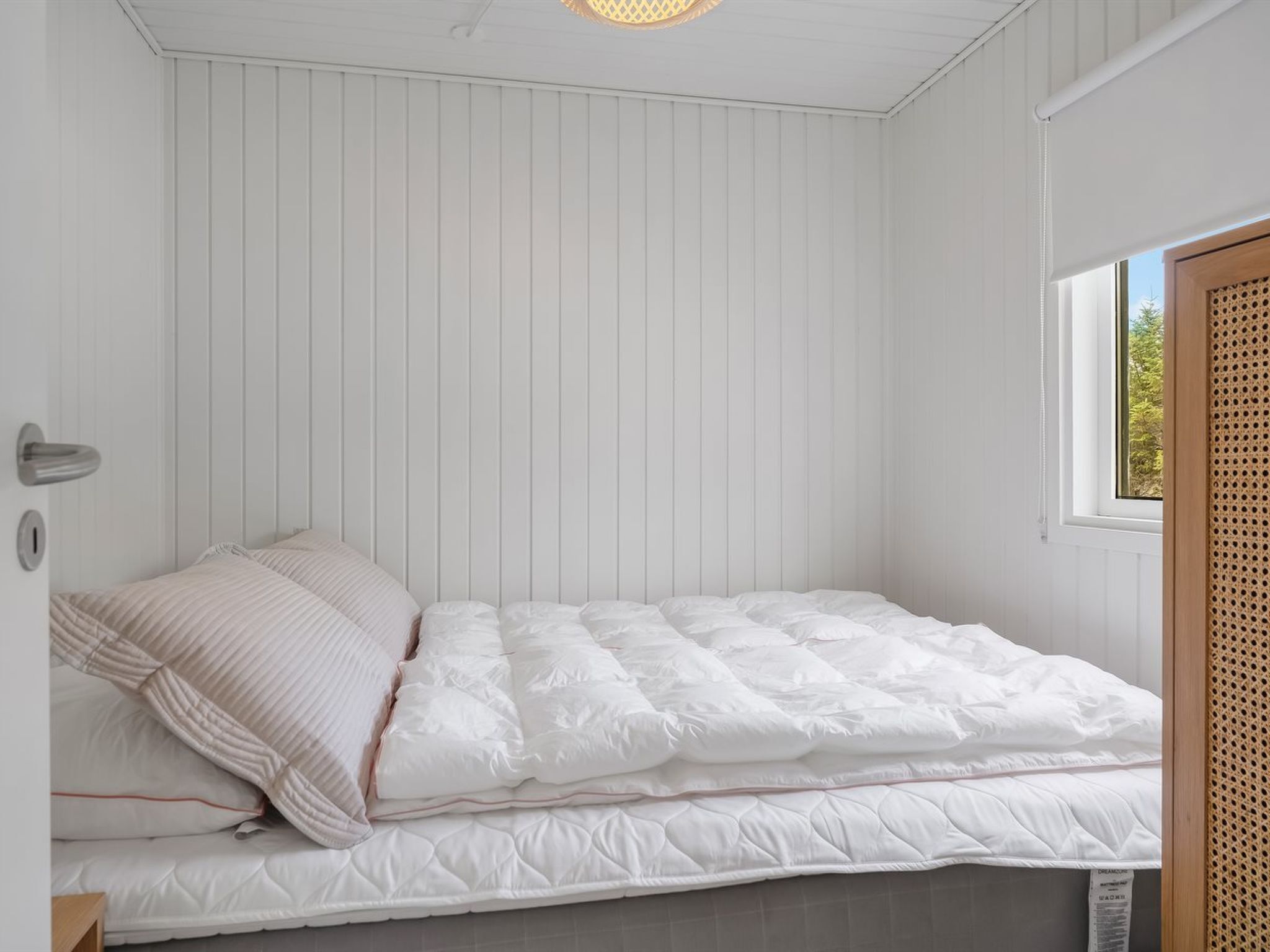 Ein Schlafzimmer mit einem Bett, weißen Wänden und einem Fenster.