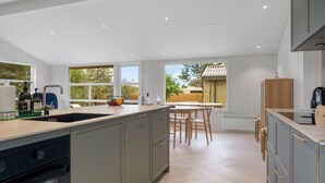 A modern kitchen with a central island, built-in appliances, and large windows offering views of the outdoors.